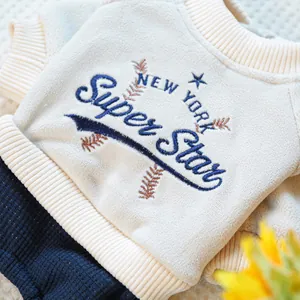 Detalle de sudadera para mascota en forro polar crema con bordado y tejido azul gofrado