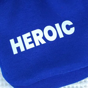 Gros plan sur l'imprimé blanc HEROIC sur le tissu en coton tricoté bleu marine