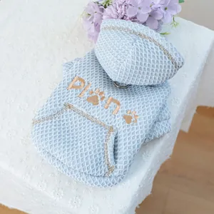 Detail of light blue waffle pet hoodie featuring gold Plan embroidery and a metal D-ring