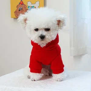 Close-up of a small white dog wearing a festive red pet hoodie with a cozy ribbed hood