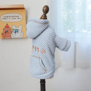 Close-up of blue waffle fabric pet hoodie with gold paw embroidery on wood model