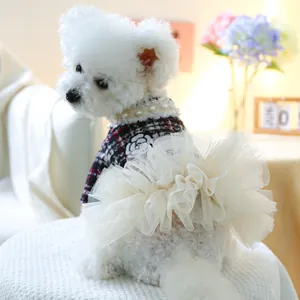 Detail eines Hundekleids mit rotem Karomuster, Perlenhalsband und weißer Kamelienblüte