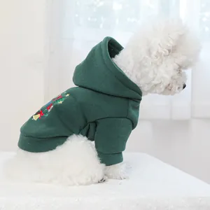 Detail of green pet hoodie with Christmas bell embroidery on a white dog