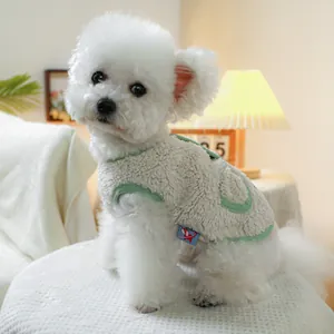 Detail of warm cream fleece pet vest with green trim on a small white dog