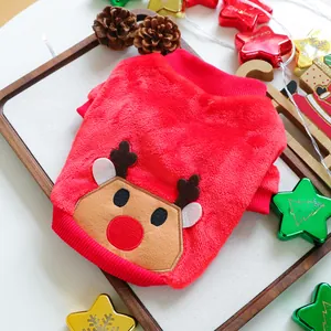 Close-up of red plush dog sweater with reindeer embroidery and Christmas decor