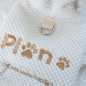 Detail of off-white waffle fabric pet hoodie with gold plan embroidery and metal D-ring