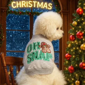 Gray knitted dog sweater with gingerbread man and OH SNAP embroidery near a Christmas tree