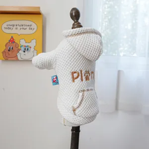 Detail of white waffle fabric pet hoodie with brown embroidery and blue side label