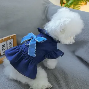 Close-up of denim pet dress with large bow, ruffled hem, and D-ring on white dog