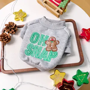 Detail of grey pet Christmas sweater with gingerbread man embroidery on a festive tray