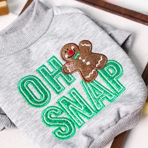 Detail of grey knitted dog sweater featuring gingerbread man embroidery and OH SNAP text