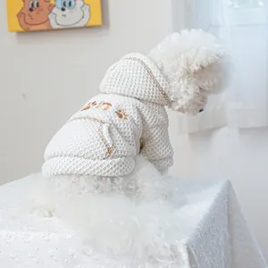 Detail of waffle fabric texture and golden paw embroidery on white dog hoodie