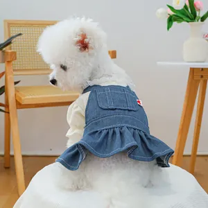 Detail of pet denim dress featuring ruffled hem and heart tag on a white floral shirt