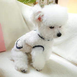Detail of warm white fleece pet vest with blue trim and leash hole on a sofa