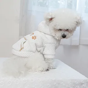 Close-up of white waffle knit pet hoodie with embroidered paw print on a small dog