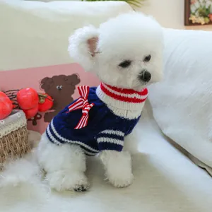 Close-up of navy pet knit sweater with red and white striped bow collar on white dog
