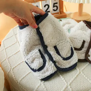 Detail of white sherpa fleece pet vest with navy trim and dark button closure