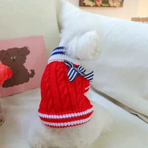 Detailed knit texture of red pet sweater with navy bow on a small white dog