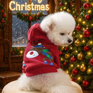 Close-up of a white dog wearing a red Christmas reindeer hoodie in a festive setting