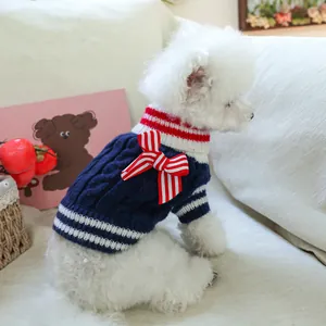 Dark blue cable-knit dog sweater with nautical bow and striped trim on white Bichon