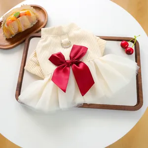 Detail of cream knit pet dress with large red satin bow and metal D-ring attachment