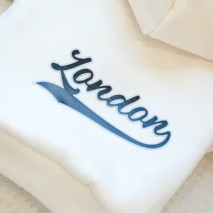 Detail of soft cream pet hoodie featuring vintage blue London lettering and knit texture