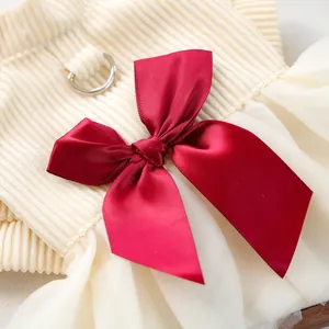 Detail of beige knit pet dress featuring a large red satin bow and metal D-ring