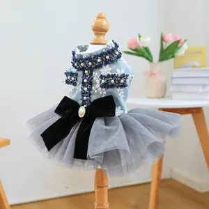 Détail d'une robe pour animal avec broderie bleue, jupe en tulle gris et nœud en velours noir