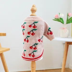 Detailed texture of pink knit pet sweater with cherry jacquard and ribbed high collar