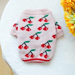 Close-up of pink pet knit sweater with red cherry jacquard and ribbed striped hem