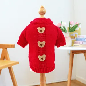 Macro detail of red knitted pet sweater with argyle patterns and cute bear embroidery