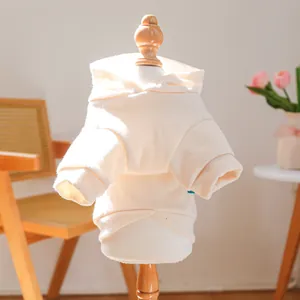 Detailed view of a beige pet hoodie on a wooden mannequin in a cozy home setting