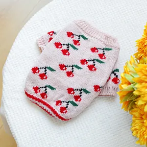 Detail of pink knit pet sweater featuring cherry jacquard pattern and ribbed edges