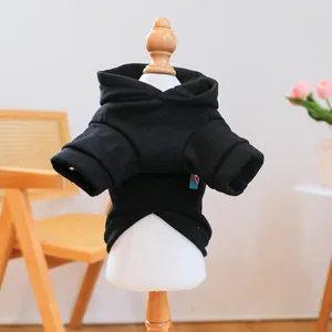 Detail view of black pet hoodie with brand tag on soft fabric and warm home background