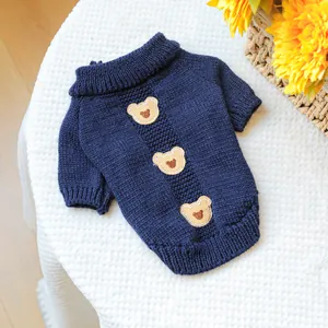 Detail of dark blue pet knit sweater with bear patches and ribbed cuffs on white mesh