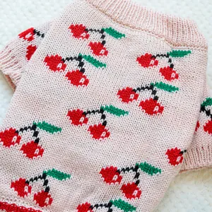 Detail of pink knitted pet sweater with cherry jacquard pattern for dogs and cats