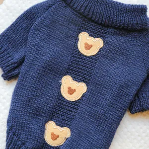 Close-up of navy blue knit pet sweater featuring three yellow teddy bear embroidery patches