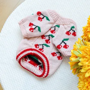 Detailed flat lay of pink pet knit sweater with cherry patterns and ribbed edges