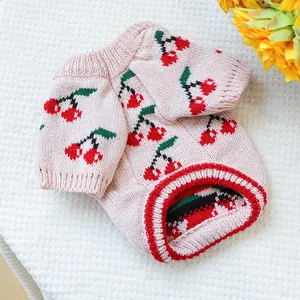 Close-up of pet knitted sweater featuring cherry patterns and ribbed knit texture