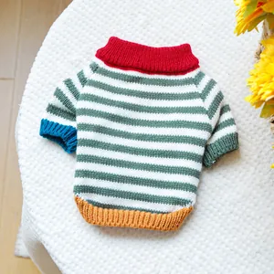 Detail of colorful striped pet sweater with red collar and yellow hem on plush background
