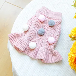 Detail of pink knitted pet dress with pom-poms and ruffled hem for dogs and cats
