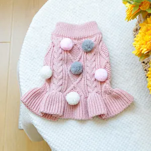 Detailed macro view of pink cable knit pet sweater with colorful pom-poms and ruffle hem