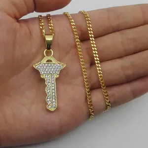 Dettaglio di un ciondolo a chiave dorata con strass scintillanti su una catena a maglia cubana