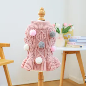 Close-up of pink pet knit sweater featuring cable knit patterns and 3D plush pompoms