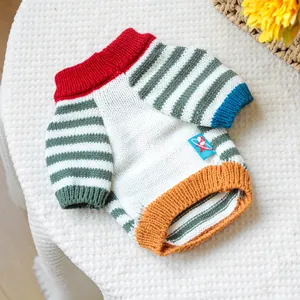 Close-up of multicolor striped knit pet sweater with ribbed cuffs and brand patch