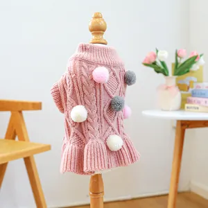 Detail view of pink knit pet sweater with decorative pom-poms and ruffled hemline