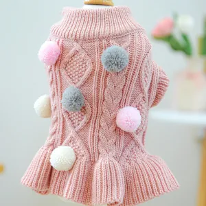 Close-up of pink knit pet sweater with diamond textures and colorful pom-pom details
