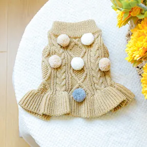 Close-up of knitted dog sweater with cable pattern and colorful pom-poms on soft fleece