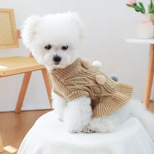 Knitted pet sweater with cable knit pattern and colorful pom-poms on a white dog