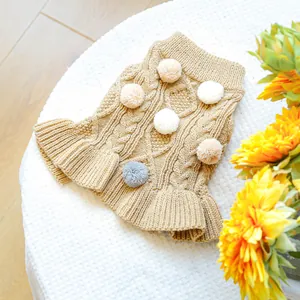 Detail of khaki cable knit pet sweater with colorful pom-poms and ruffled skirt hem